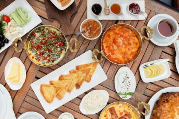 Traditional azerbaijani Turkish breakfast with egg dish, pancakes, fresh salad, jam, cheese, honey
