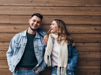 Glamorous girl in white scarf looking at boyfriend with love. indoor portrait of handsome european man spending free time