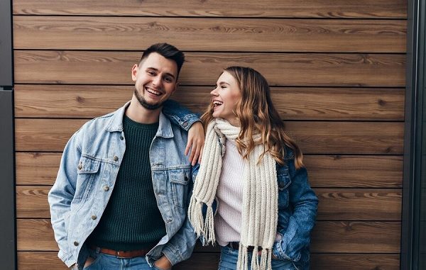 Glamorous girl in white scarf looking at boyfriend with love. indoor portrait of handsome european man spending free time