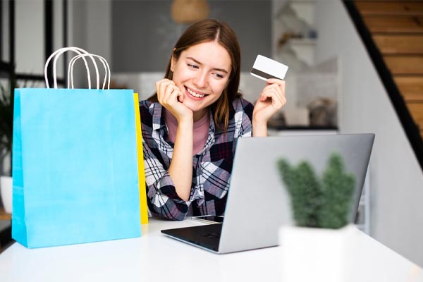 happy-woman-showing-credit-card-looking-at-laptop