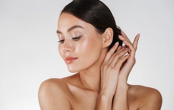 Close up of relaxed brunette woman with clean skin posing at camera with closed eyes, isolated over white