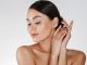 Close up of relaxed brunette woman with clean skin posing at camera with closed eyes, isolated over white